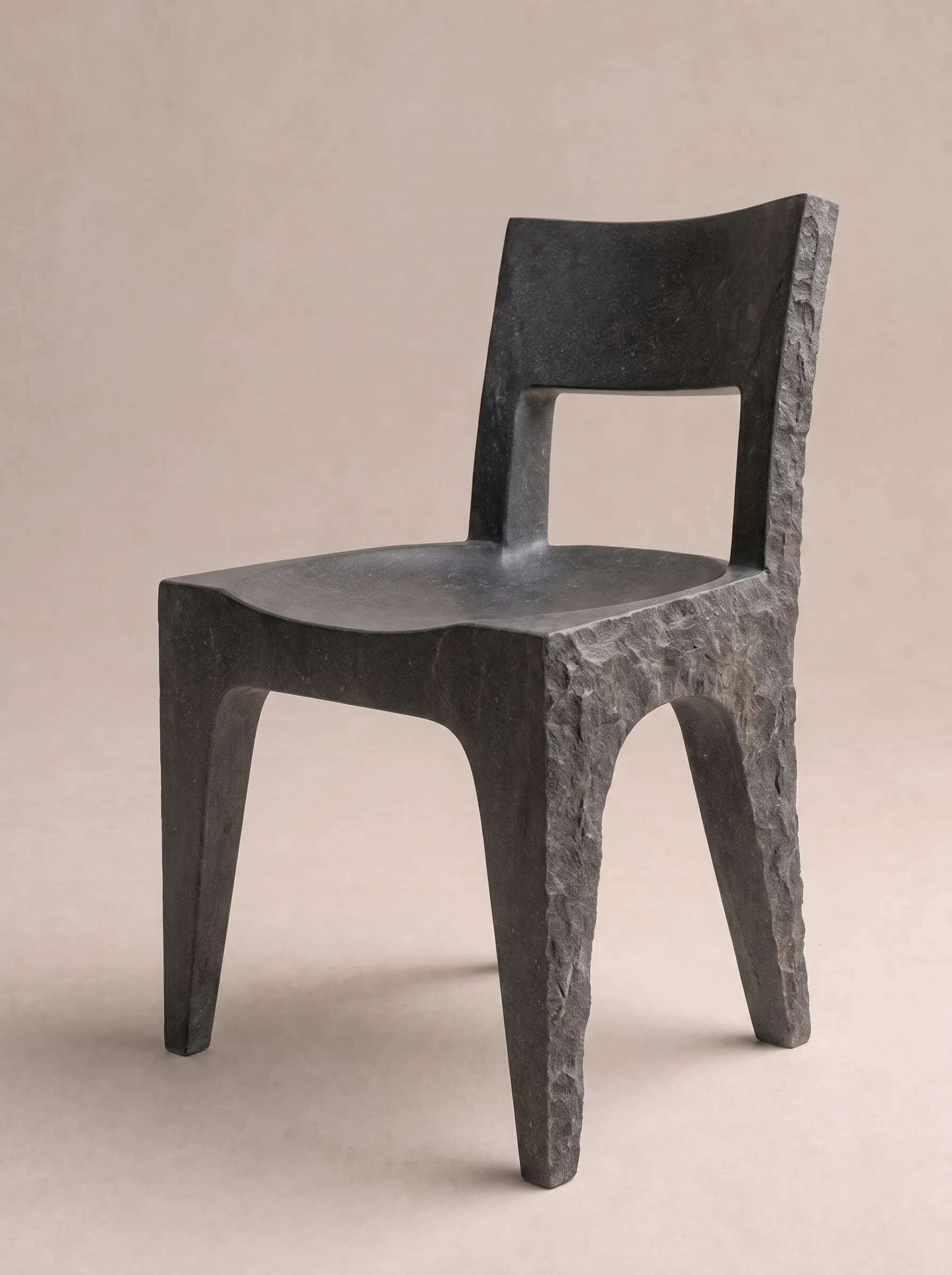 A dark basalt dining chair with a hewn seat and a tall open back
