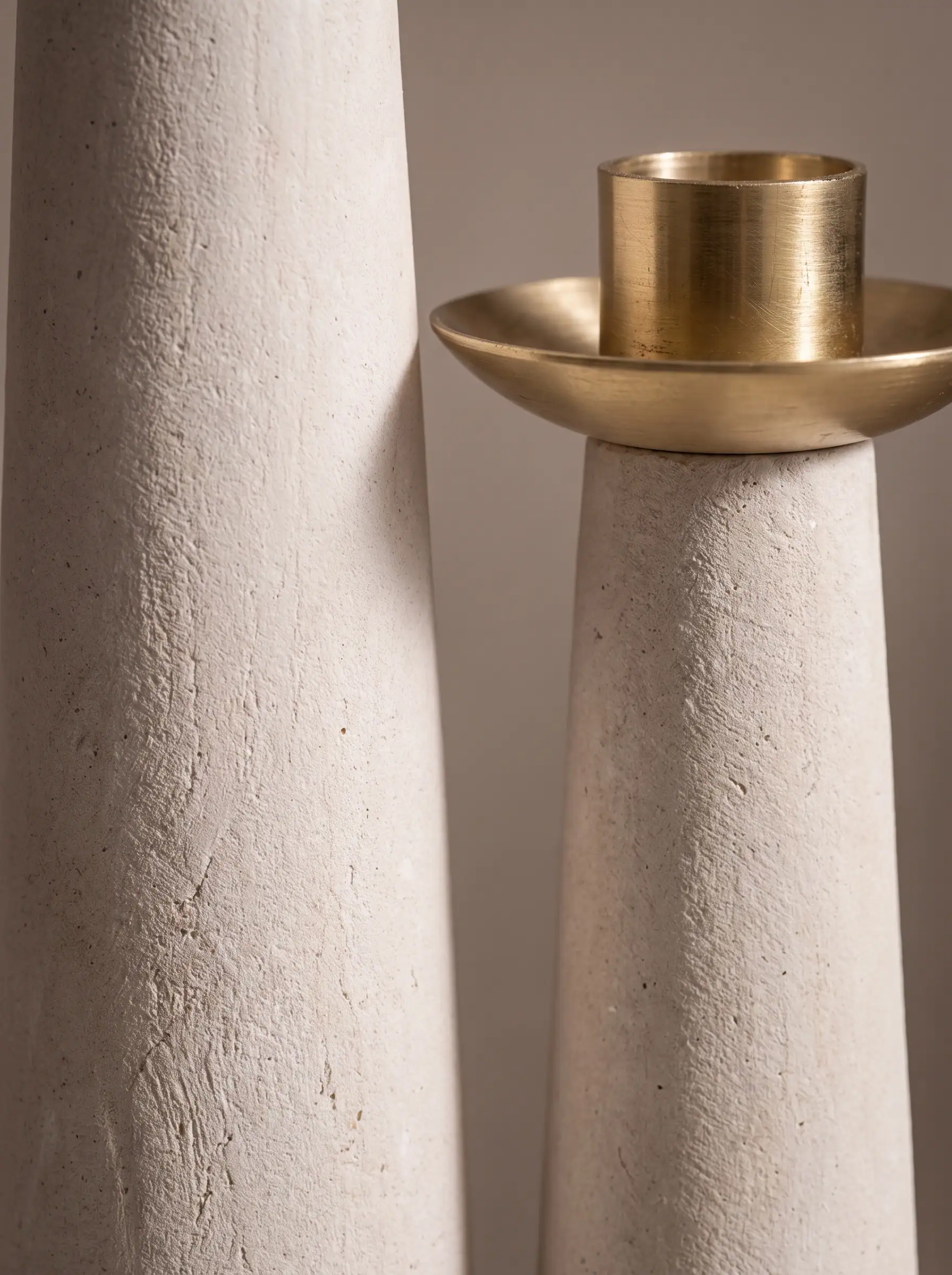 A pale stone column topped with a brass bowl, close crop