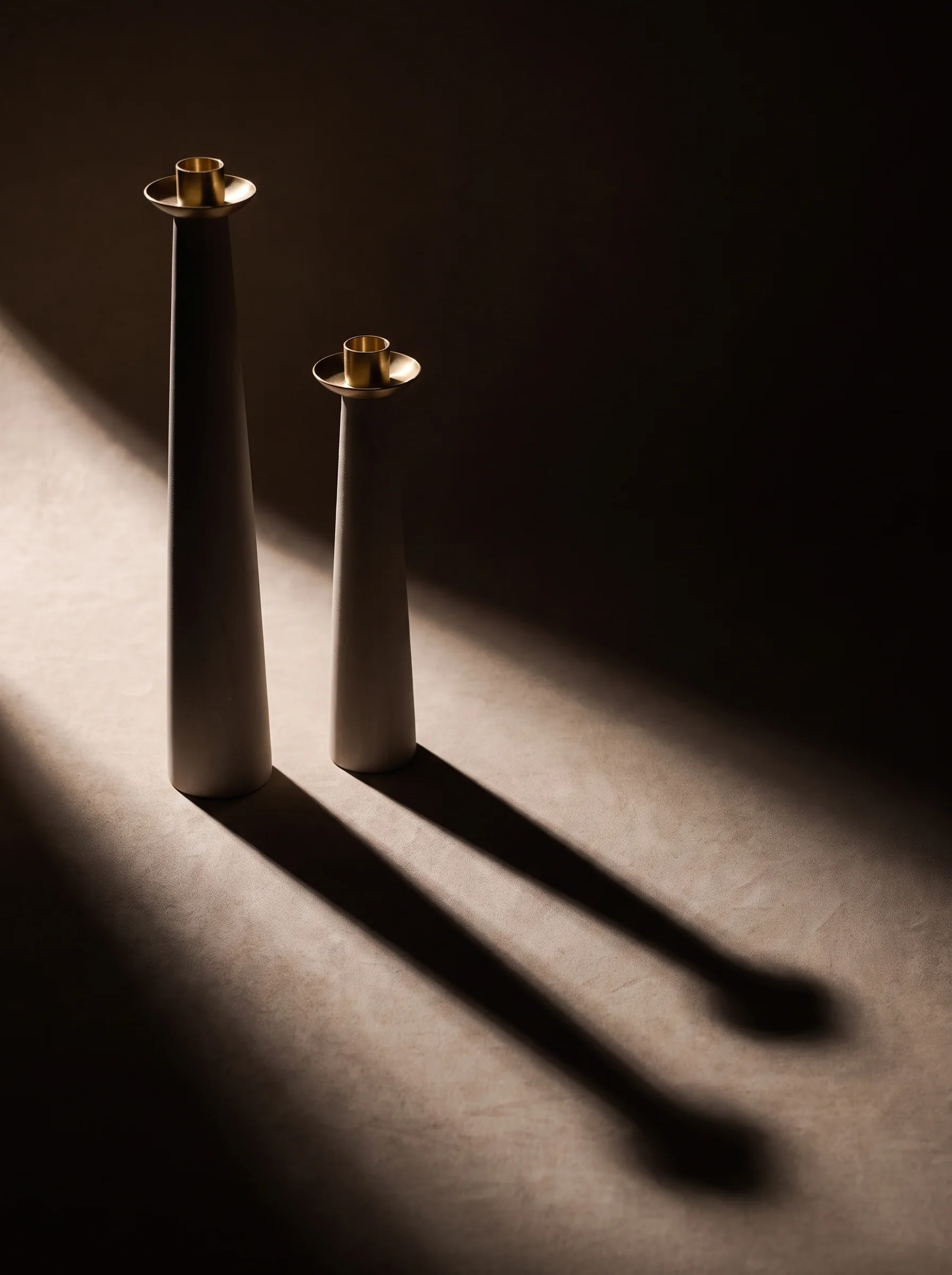 Raking light and a long shadow on a pale column with a brass top