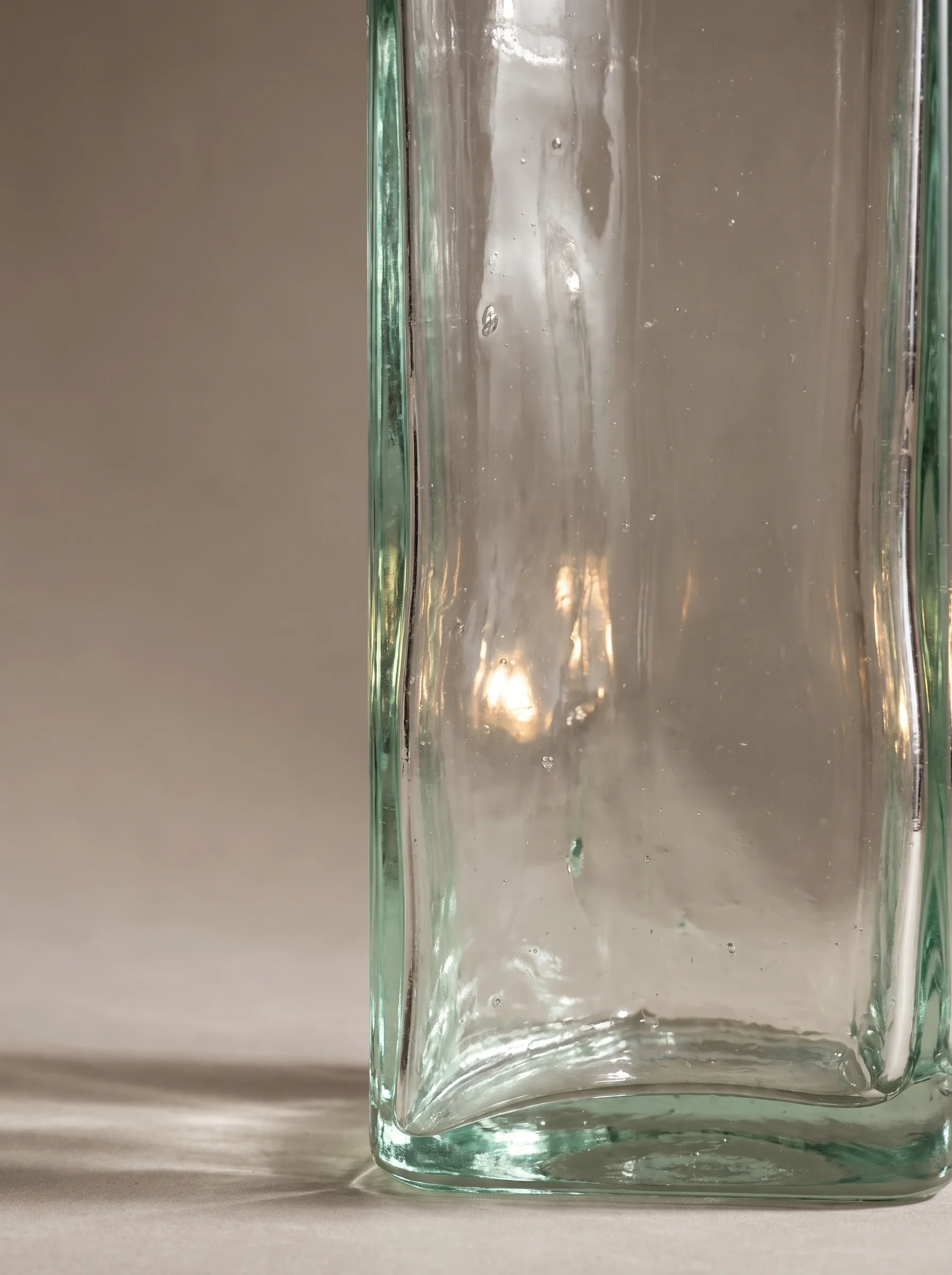 Macro of a thick hand-blown glass vessel with bubbles and warm reflections