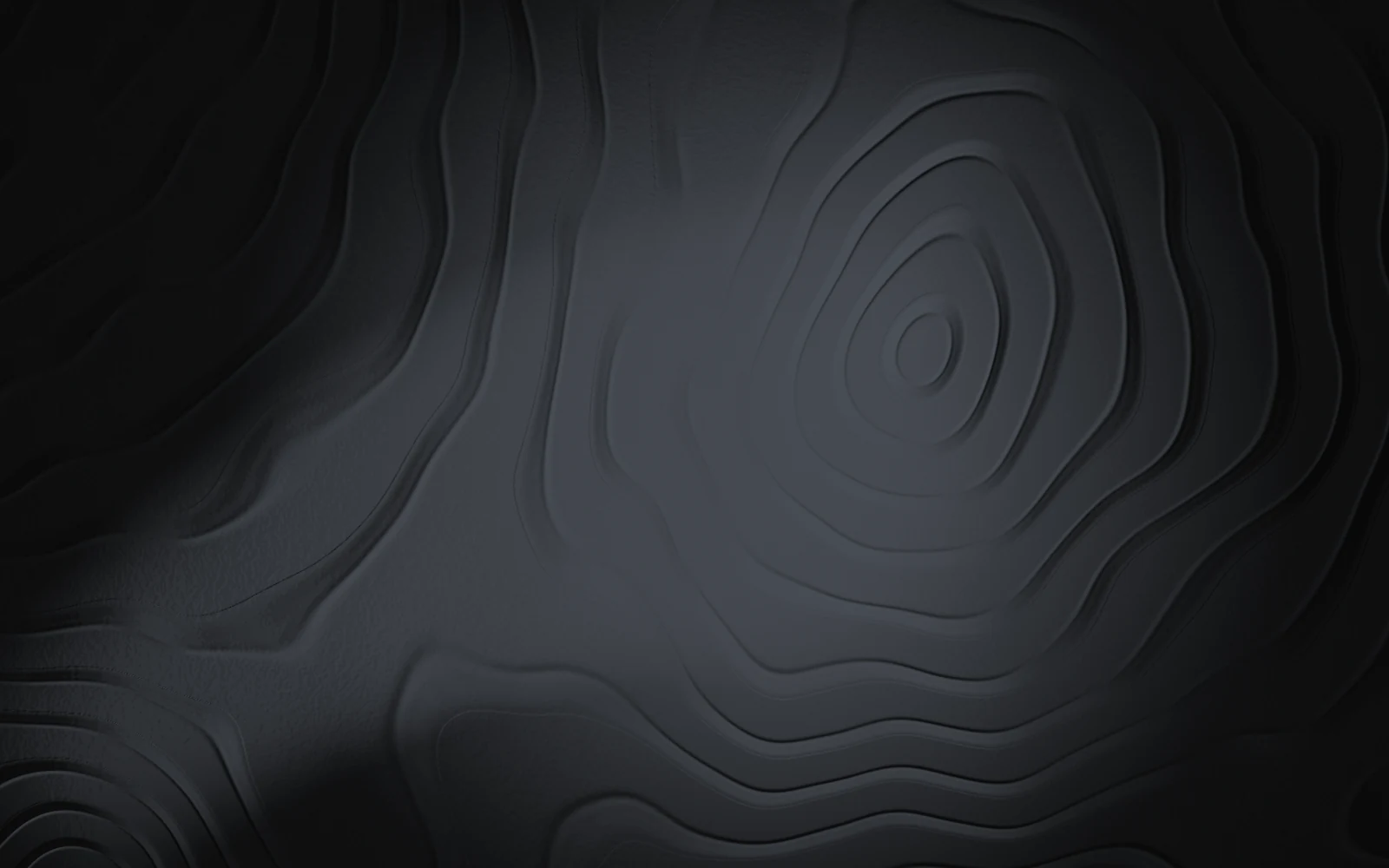A dark carved topographic relief, stepped contour lines around a raised centre, lit by a soft cool light